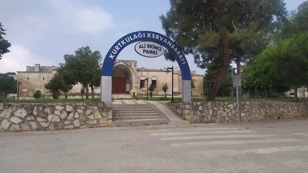 Kurtulağı Kervansarayı'nın büyük giriş kemeri ve çevresindeki park alanı