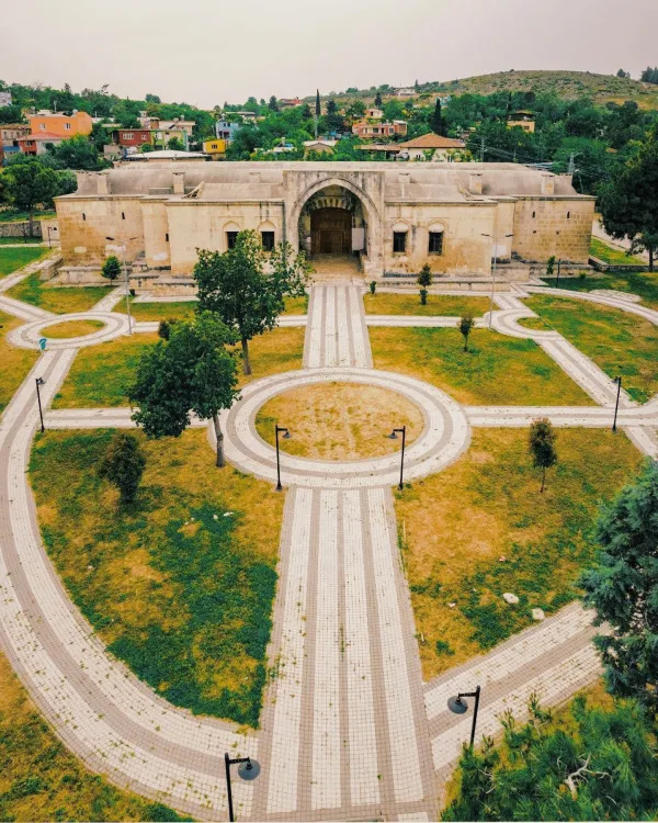 Kurtkulağı Kervansarayı'nın taş cephesi ve çevresindeki yeşil alanlar