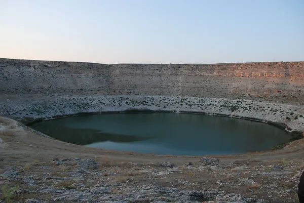 Sakin su birikintisi ve çevresindeki kayalık alan, akşam turuncu ışığıyla huzur veriyor.