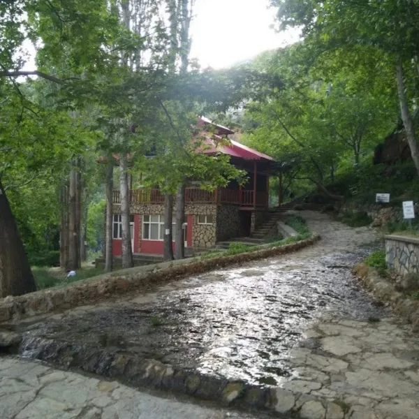 Ağaçlarla çevrili alanda kırmızı çatılı bir yapı ve taş yol görünümü.