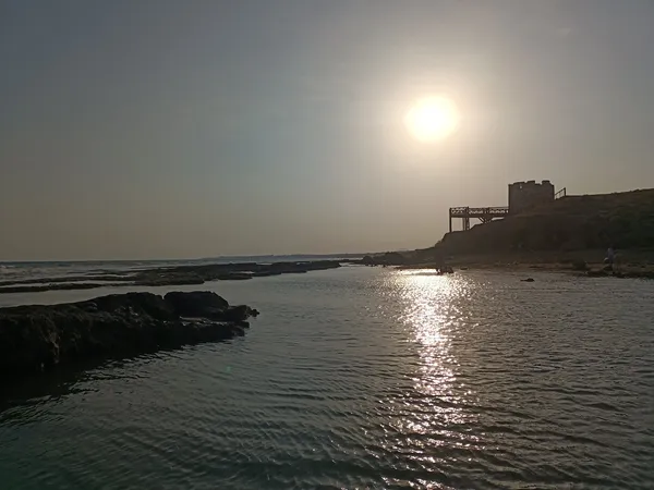 Gün batımında Süleyman Kulesi'nin arka planda yer aldığı huzurlu deniz manzarası.