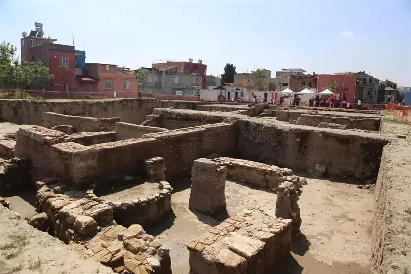 Tepebağ'da tarih ve modernite: Kalıntılarla dolu bir dünya! Açık bir arkeolojik alanda tarihi duvar kalıntıları ve modern binalar görünmekte.