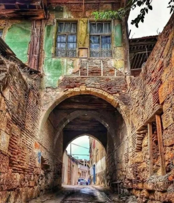 Dar sokakta uzanan taş yapılar ve kemerli geçit, geçmişi yansıtıyor.