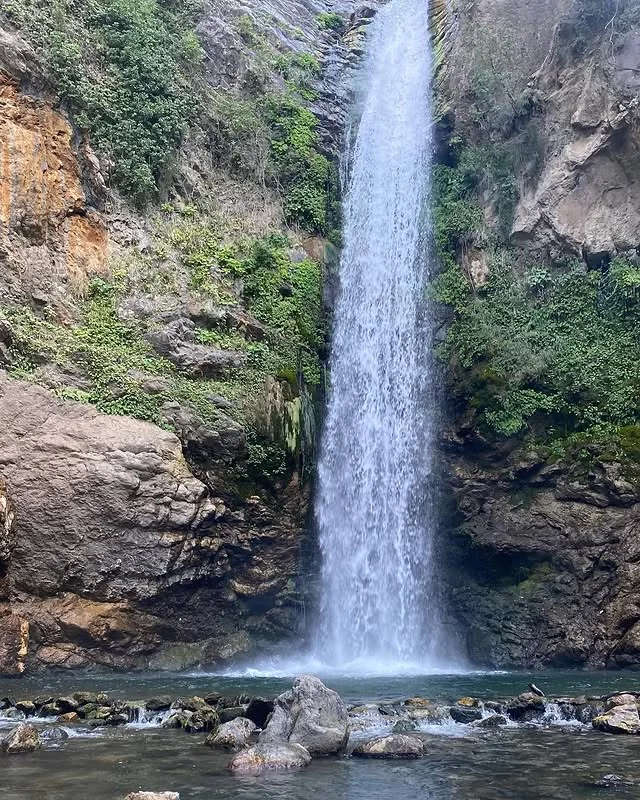 Doğanın Güzelliği - Kaya Arasından Düşen Su Kaya arasından düşen su, etrafında yeşil bitkiler ve büyük kayalarla huzur veren bir doğa manzarası oluşturuyor.