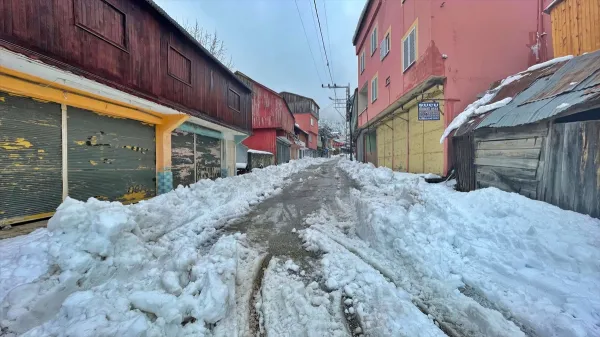 Karla kaplı dar sokak ve kapalı dükkanlar, soğuk ve gri bir hava