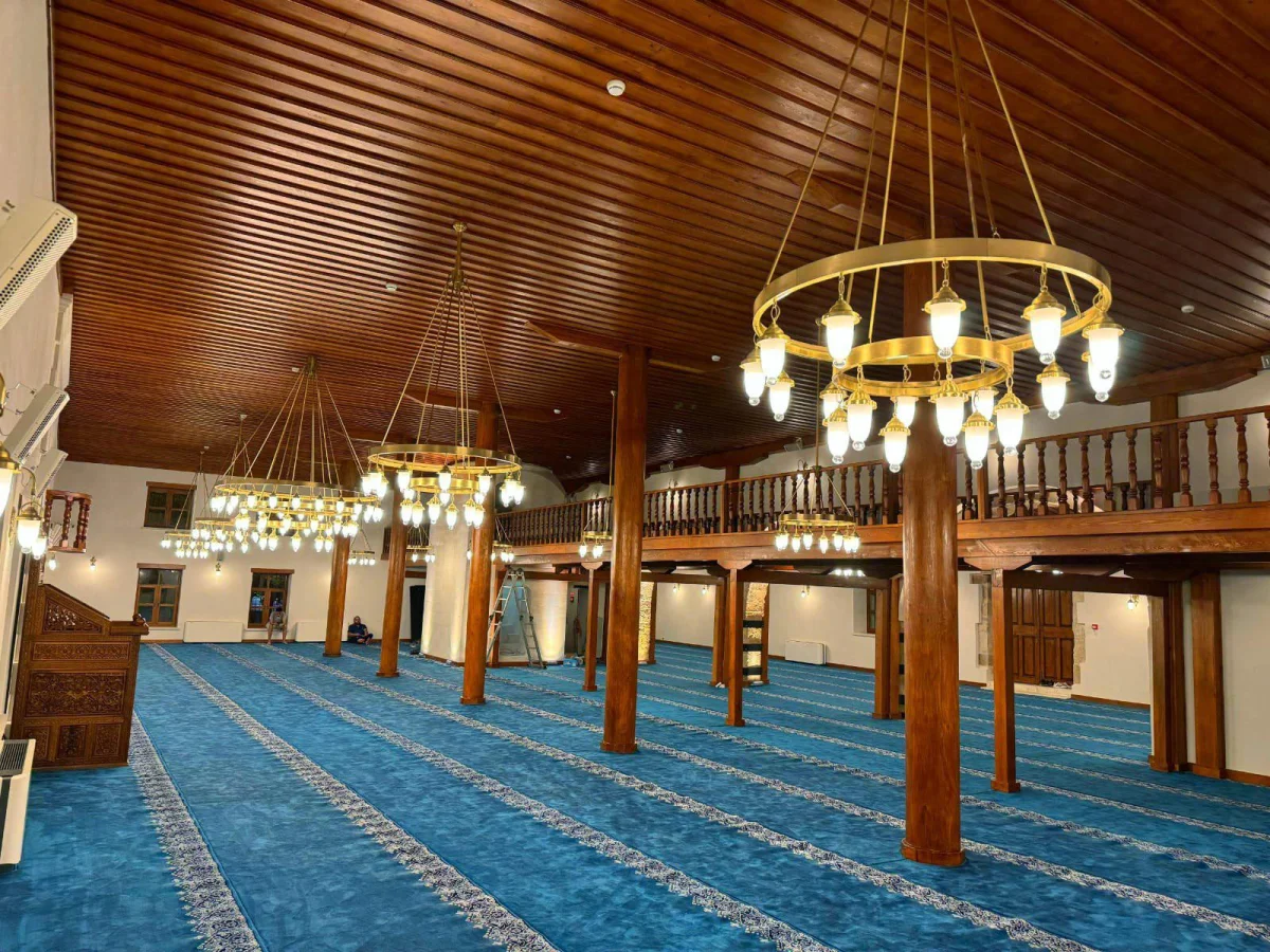 Ağcabey Camii'nin Göz Alıcı İç Mekanı - Tarih ve Estetiğin Dansı! Ağcabey Camii iç mekanında ahşap tavan, avizeler ve mavi halı detayları