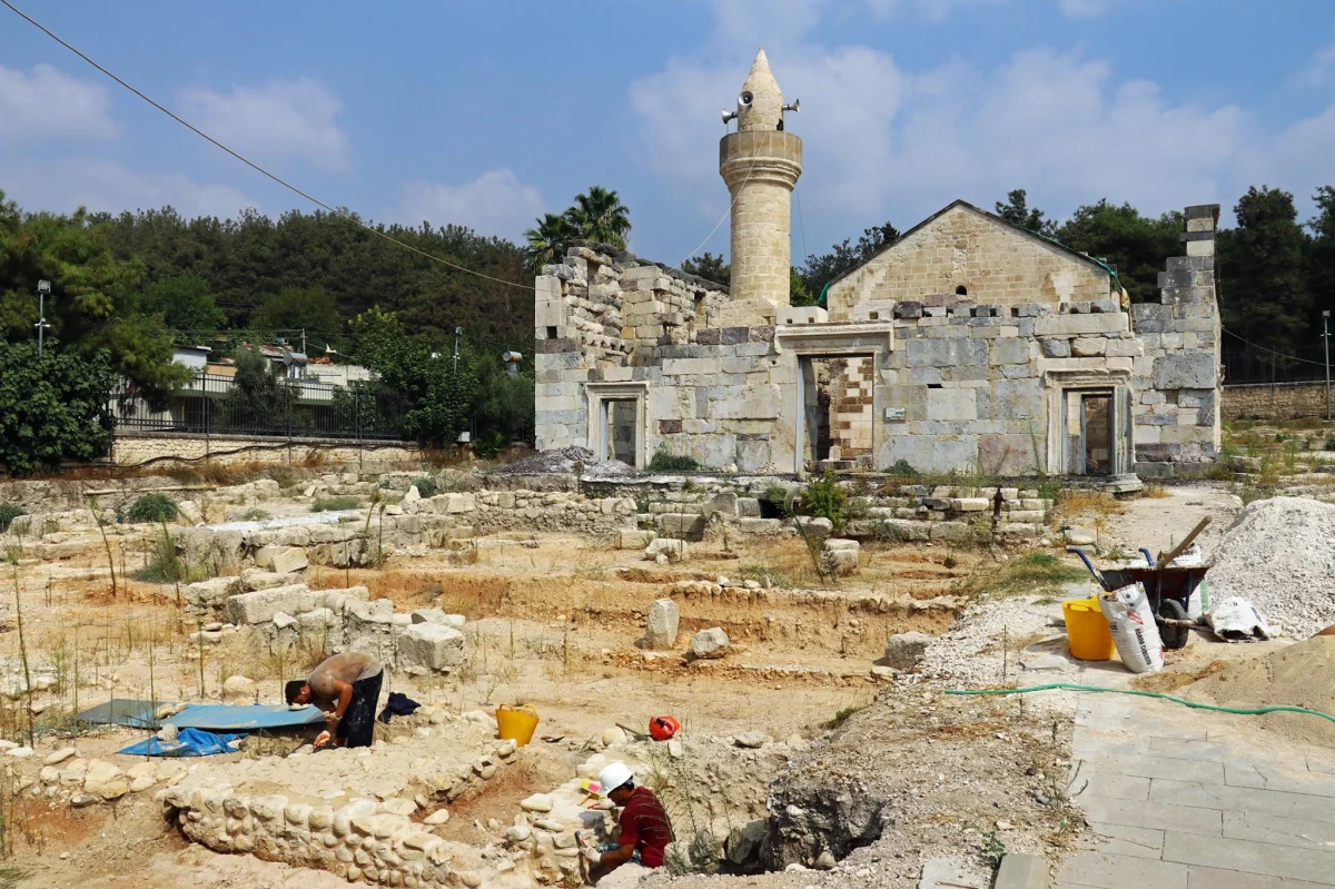 Kazı alanında çalışan işçiler ve arka planda yıkılmış tarihi cami