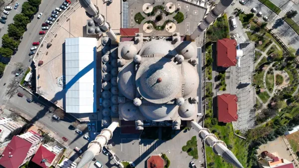 Geniş bir caminin üstten görünümü, yüksek minareler ve yeşil alanlar