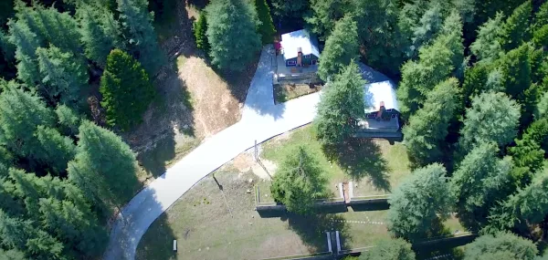 Yoğun ağaçlık alanda prefabrik evler ve kıvrılan bir yol görünümü.