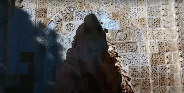 Sanatsal taş duvar, geometrik şekiller ve çiçek motifleriyle bezeli.