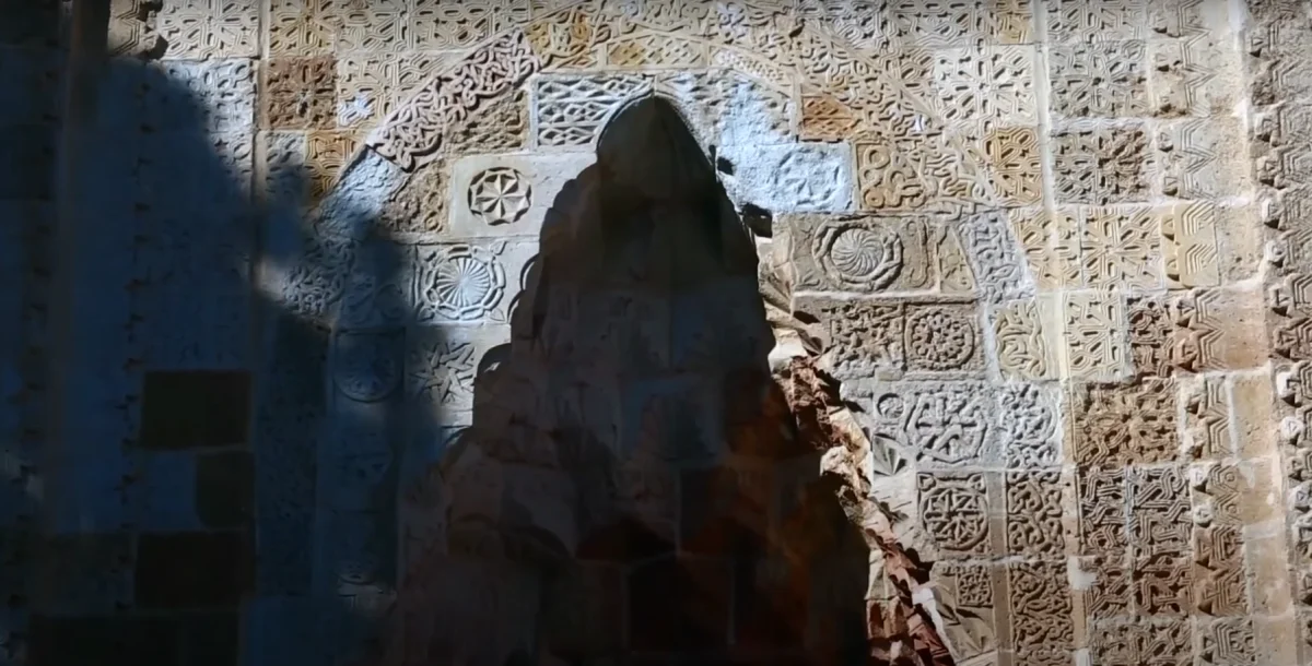 Eşsiz İşçilik - Eshabı Kehf Külliyesi'nin Sanatsal Duvarları Sanatsal taş duvar, geometrik şekiller ve çiçek motifleriyle bezeli.