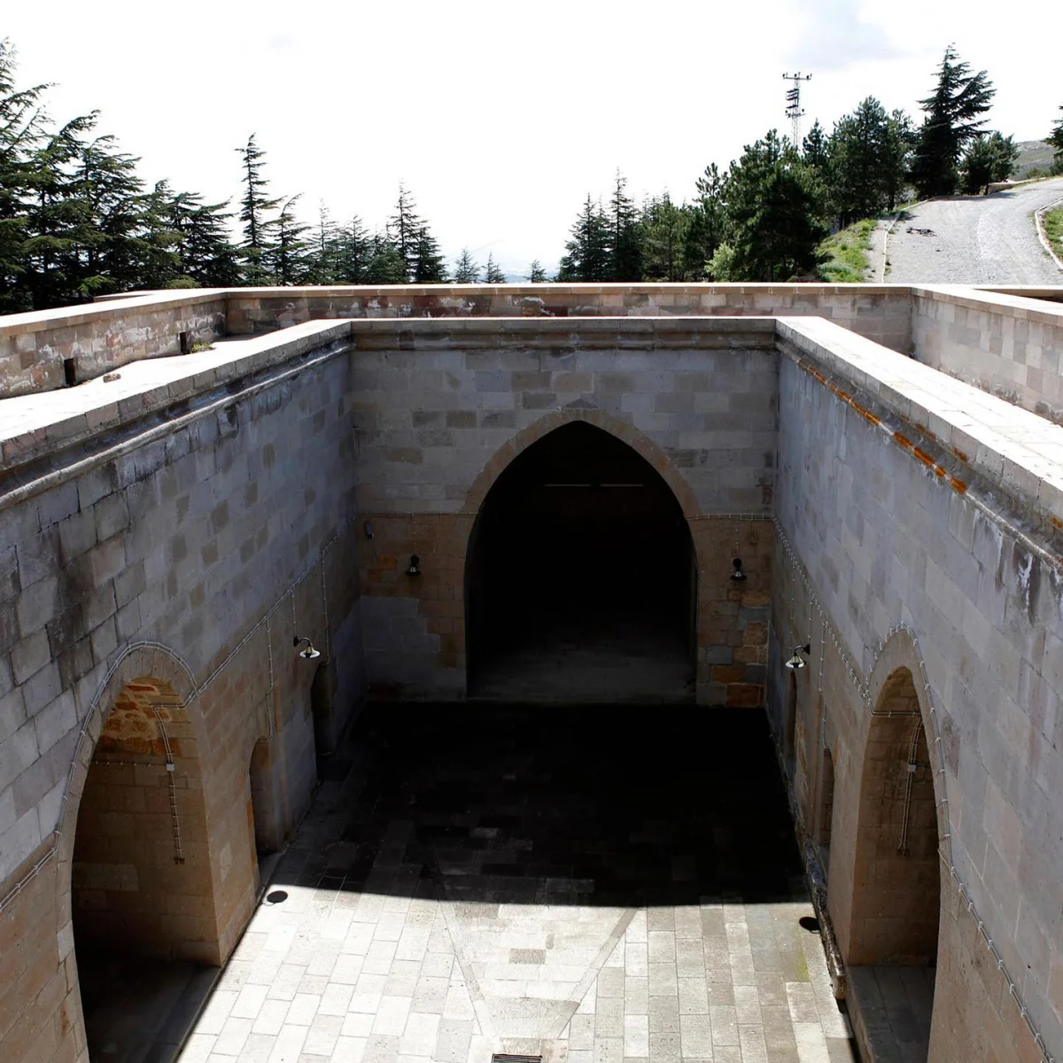 Eshabı Kehf Külliyesi'nin İç Mekanı - Taş Duvarların Zenginliği Tarihi yapının içi, taş duvarlar, kemerli kapılar ve taş döşeme ile çevrili.