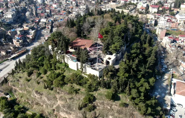 Kahramanmaraş Kalesi, ağaçlarla çevrili tepede dalgalanan bayraklar ile birlikte görülüyor.