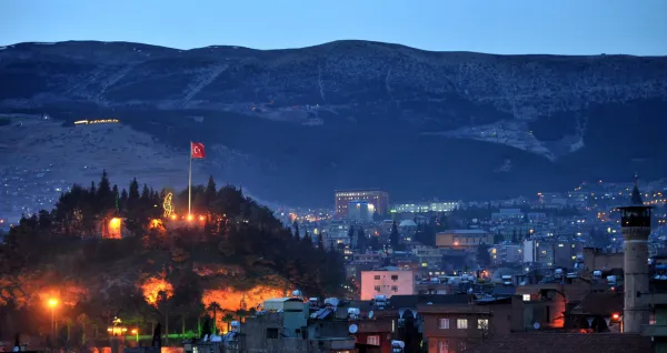Kahramanmaraş'ın gece manzarasında aydınlatılmış kale ve dağlar görünmekte.