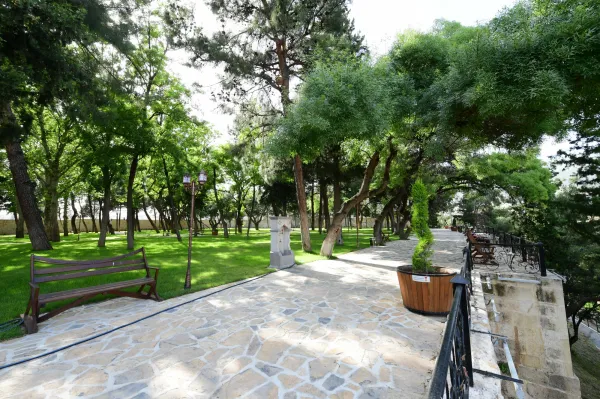 Yemyeşil ağaçlarla çevrili park alanında yürüyüş yolu ve ahşap banklar