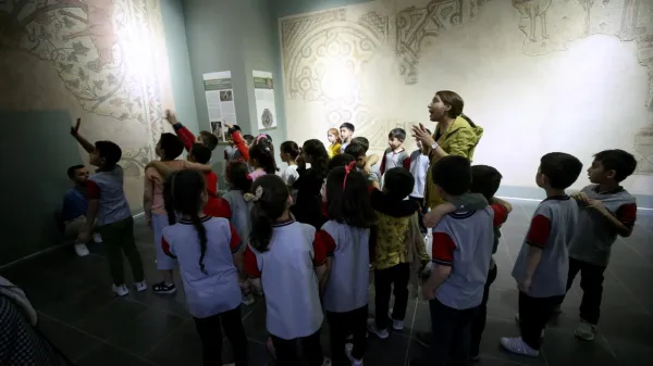 Çocuklar, müzedeki öğretmenin yanında antik fresk hakkında bilgi alıyor.