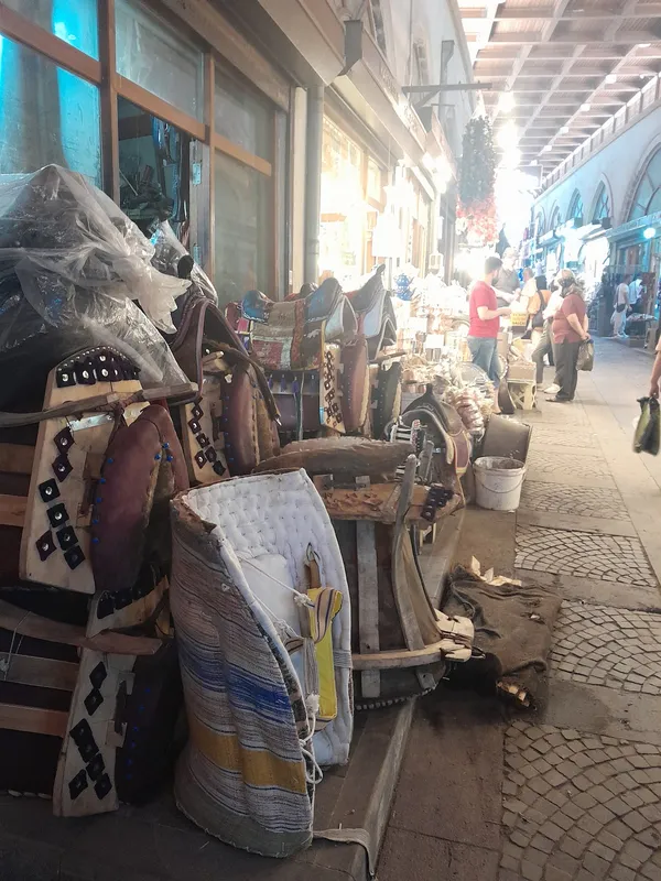 Ahşap tezgahlar önünde odun ve mendil dolu sokak manzarası.