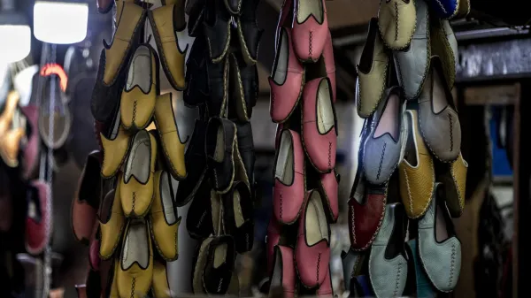 Dükkan içinde asılı geleneksel ayakkabılar, farklı renk ve dikiş detaylarıyla dikkat çekiyor.