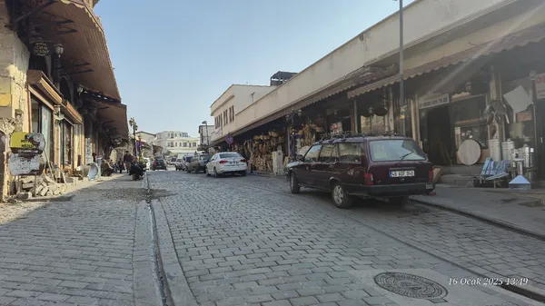 Dükkanlarla çevrili, taş döşemeli dar bir sokak görüntüsü.