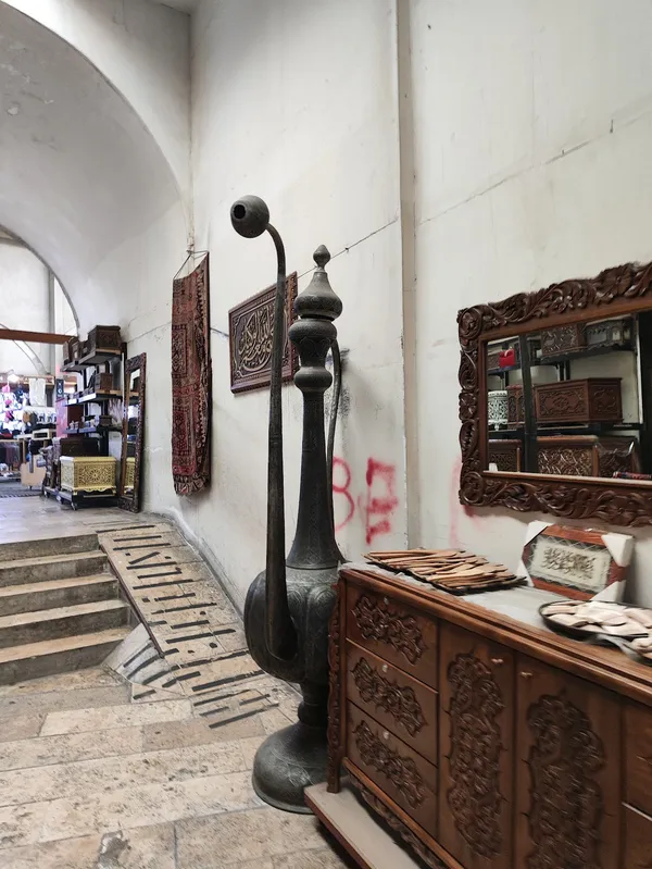 Tarihi bir çarşıda dekoratif unsurlar, oyma dolap ve müzik aleti görülüyor.