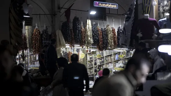 Kalabalık bir pazar yerinde kurutulmuş meyveler ve baharatlar sergileniyor.