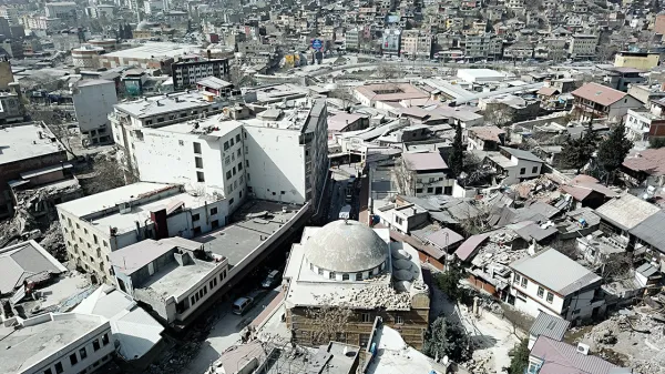 Yüksek açıdan çekilmiş bir şehir manzarası, çeşitli binalar ve dar sokaklar görünmekte.