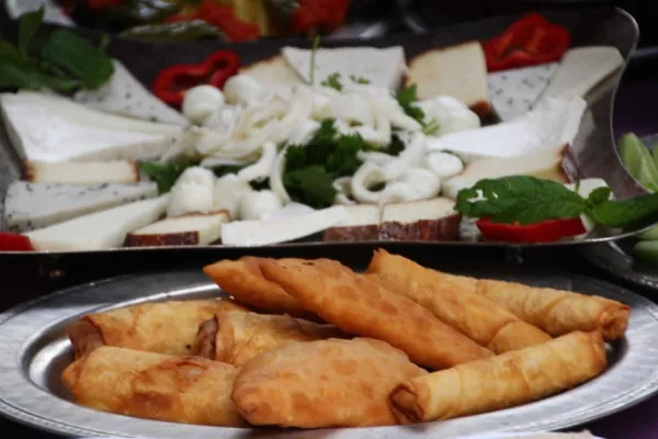 Metal tepsi üzerinde kızartılmış simit, börek, peynir ve sebzelerin yer aldığı sağlıklı bir meze sunumu