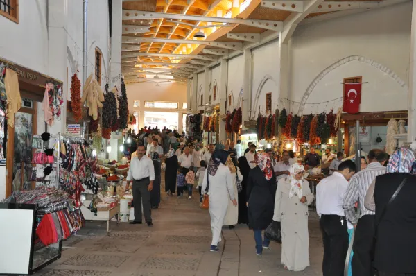 Kalabalık pazar sokağında tezgahlar, baharatlar ve Türk bayrağı