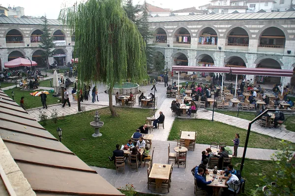 Tarihi avluda kafeler ve restoranlarla dolu yeşil alan.