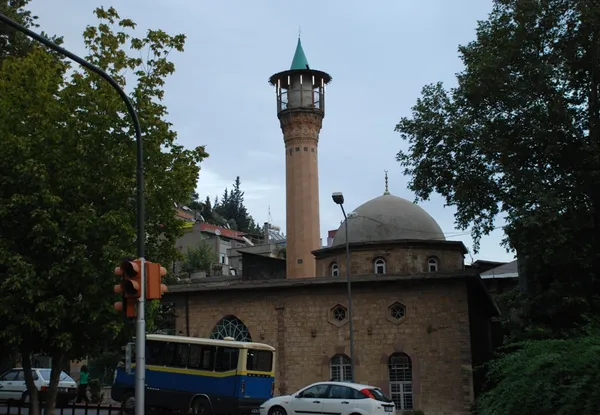 Huzur veren taş cami, yuvarlak kubbe ve uzun minaresiyle tarihi bir yapı.
