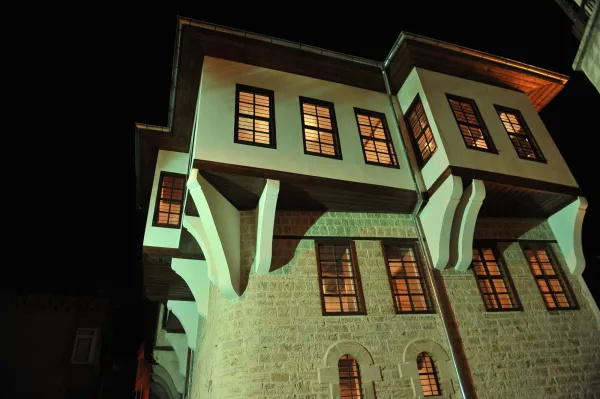 Geceleri aydınlatılmış Dedeoğlu Konağı'nın taş ve ahşap cephe detayları.