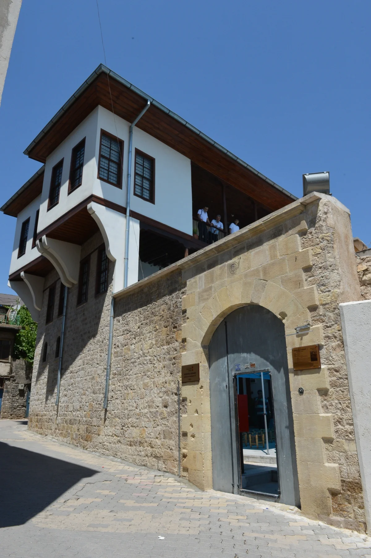 Tarihin Modern Yüzü: Tarihi taş duvarlar ve modern detaylar bir arada! Tarihi taş duvar önünde modern bina, geniş pencereler ve balkonlar.