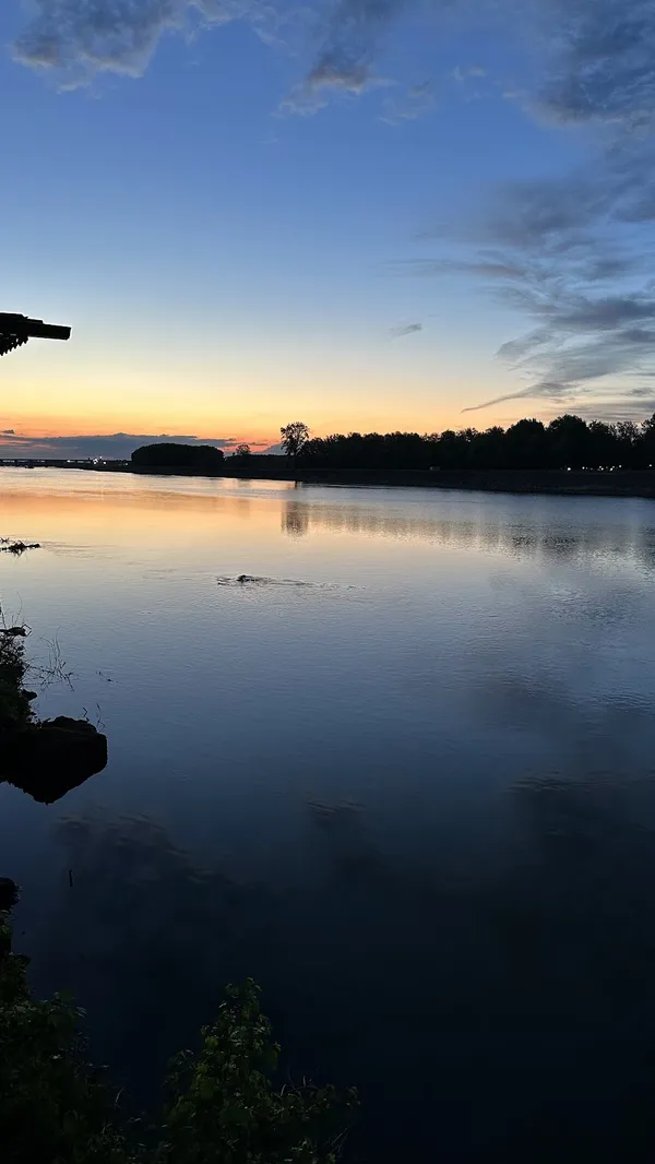Güneş batımında nehir, ağaçlar ve geleneksel yapı silueti