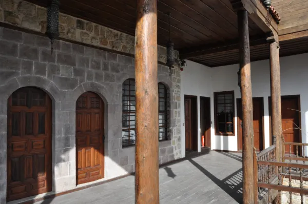 Tarihi bir yapının ön cephesi, ahşap kapılar ve taş duvarlar ile sıcak bir atmosfer sunuyor.