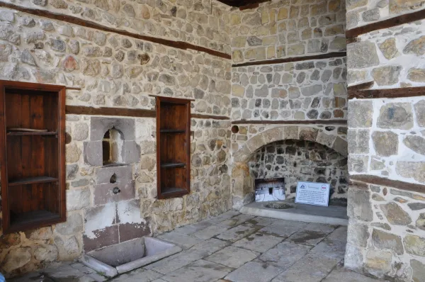 Taş ve ahşap malzemelerle yapılan duvar, içindeki çeşme ve raflarla rustik bir estetik sunuyor.