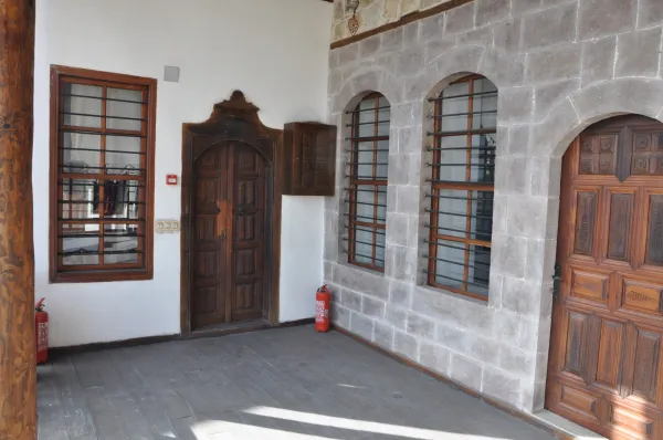 Tarihi iç mekanda doğal taş duvarlar, ahşap zemin ve detaylı tahta kapı görülüyor.