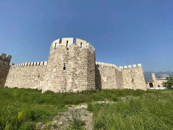 Taşlardan inşa edilmiş Payas Kalesi'nin yüksek kuleleri ve çevresindeki yeşil alanlar