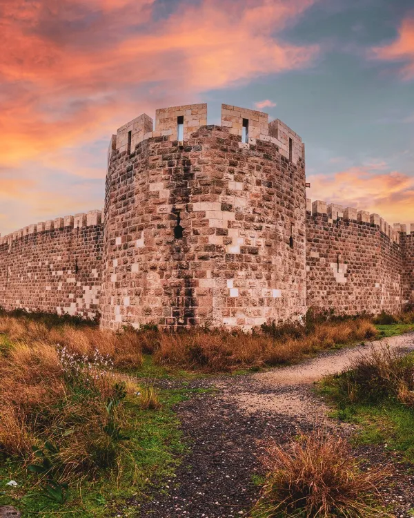 Tarihi Payas Kalesi, pastel tonlarda gün batımı ile çevrili doğal alan.