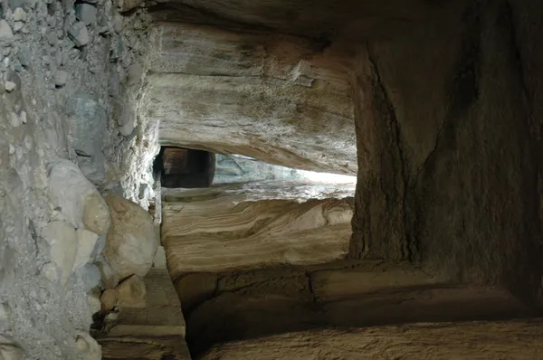 Büyük bir kanyon görünümünde dar geçit, yüksek kayalık duvarlar ve ışık alan açıklık.