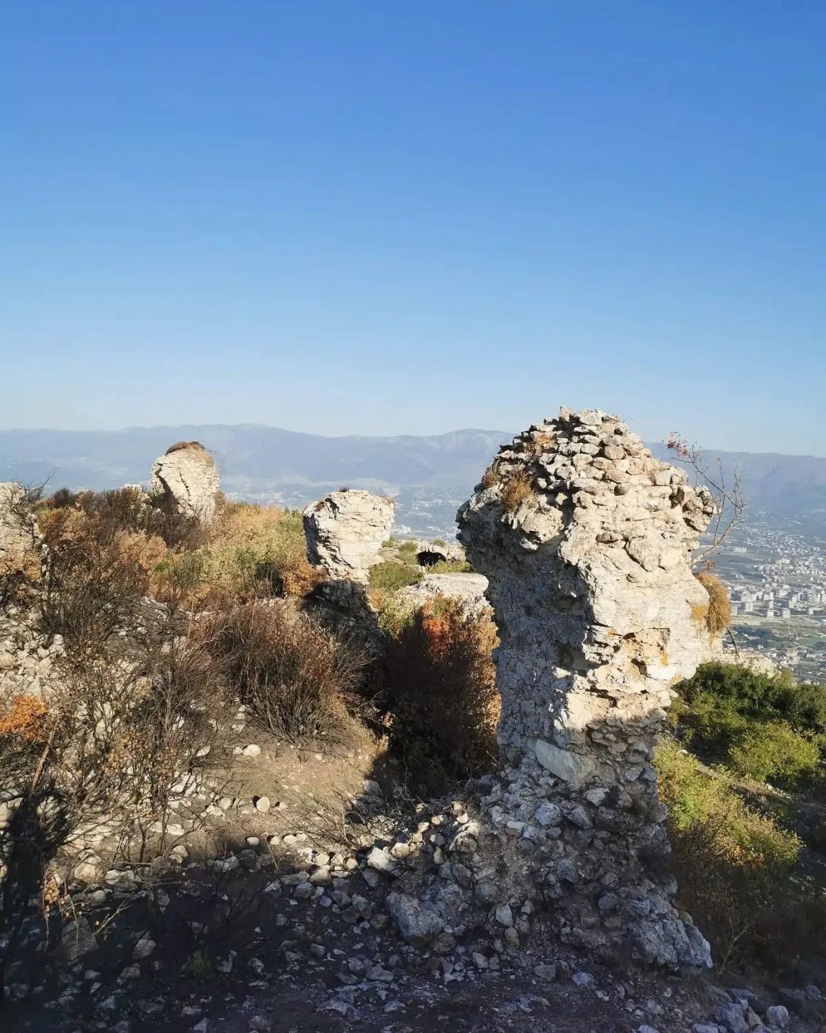 Antakya Kalesi: Tarihin İzleri - Taş kalıntılar ve yanmış bitki örtüsü! Yüksek dağlık alanda yer alan Antakya Kalesi'nin taş kalıntıları ve çevresindeki yanmış bitki örtüsü.