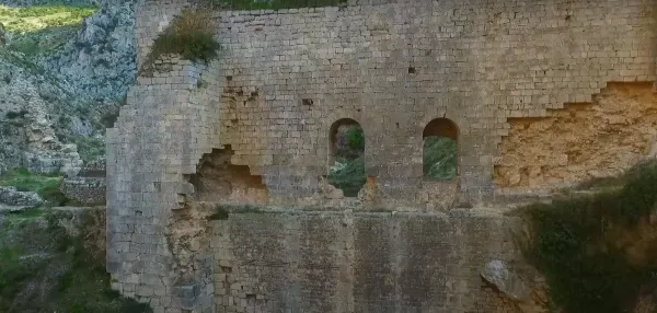 Tarihi taş duvarları ve yuvarlak pencereleriyle Antakya Kalesi, yeşil alan ve dağlarla çevrili.