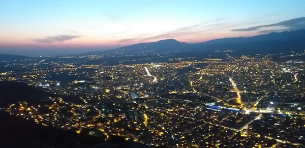Şehir manzarası, gün batımında pembe ve mavi gökyüzü ile aydınlanmış.