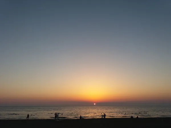 Arsuz plajında gün batımında dalgalar ve dinlenen insanlar