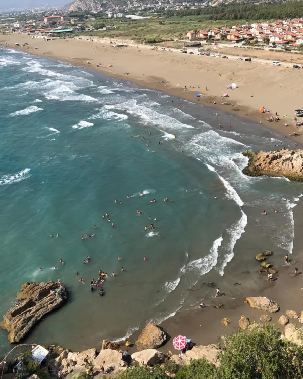 Geniş plajda güneşlenen insanlar ve mavi deniz manzarası