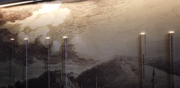 Dağlık manzara, bulutlu gökyüzü ve metinlerle süslü şeffaf sütunlar.