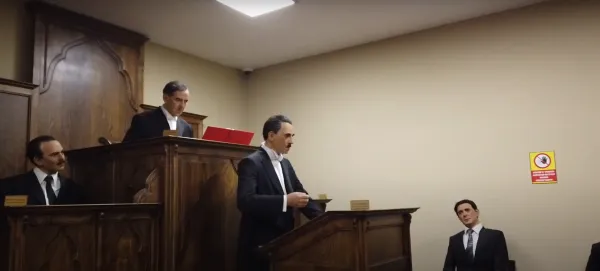 Mahkeme salonunu andıran sahnede, kuklalardan yapılmış figürler ve uyarı levhası görünmekte.