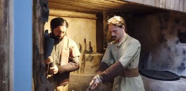 Tarihi atölyede tüfek tutan adam ve nesneye odaklanan diğer adam