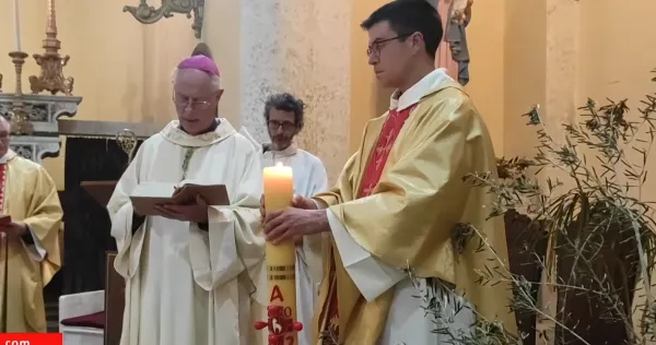 Piskopos dua ederken, yanında mum tutan yardımcı ile sıcak bir atmosferdeki dini tören