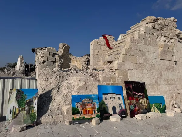 Yıkık yapının önünde sergilenen renkli resimler ve açık mavi gökyüzü