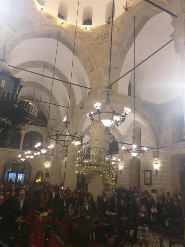 Yüksek tavanlı, taş duvarlı bir kilisenin iç mekânında insanlar ve dini semboller